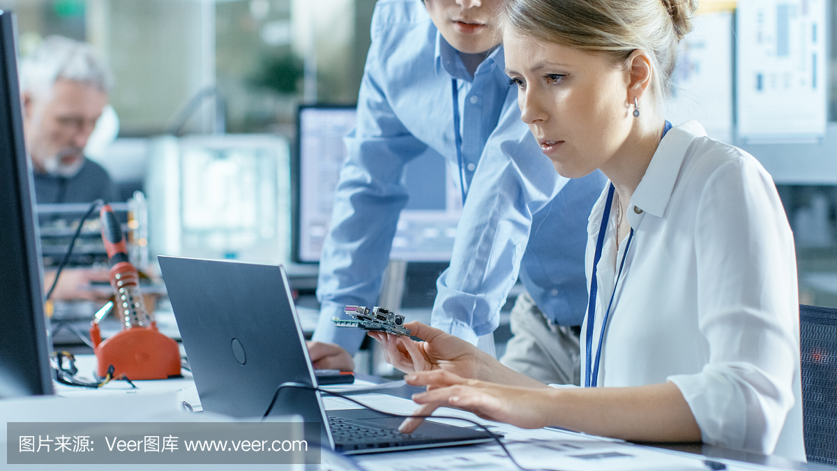 女計算機科學家將電路板連接到她的筆記本電腦并開始編程。她在先進技術實驗室工作。